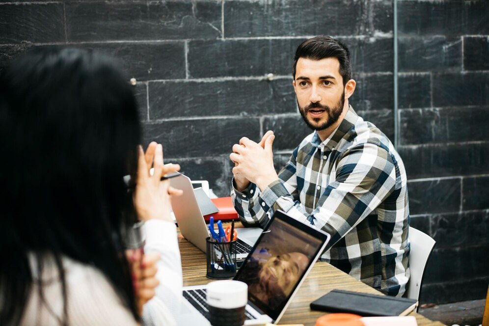 coworkers-discussing-while-sitting-desk-office_1048944-2596586
