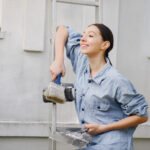 Cute girl standing near wall with repair tools