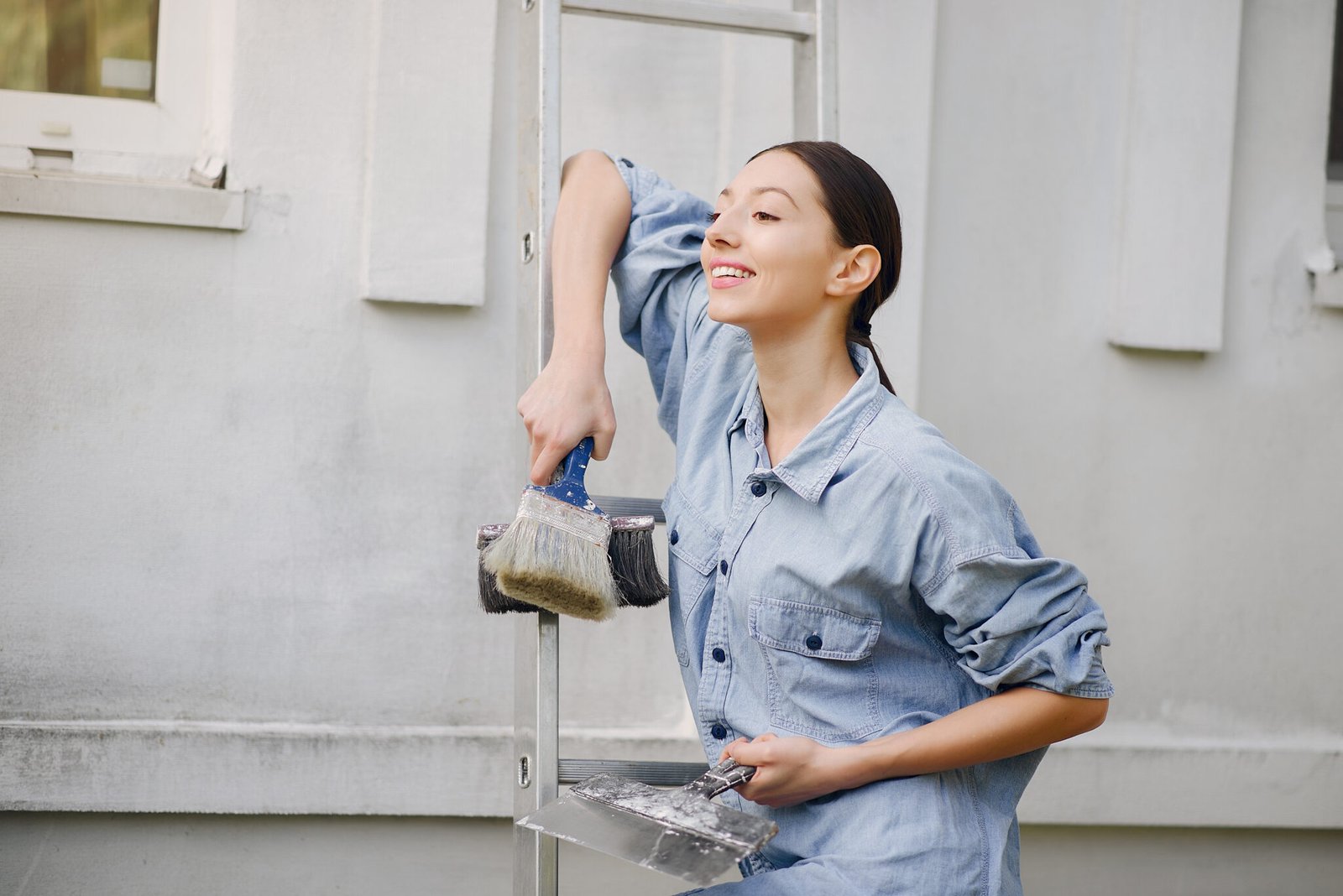 Cute girl standing near wall with repair tools